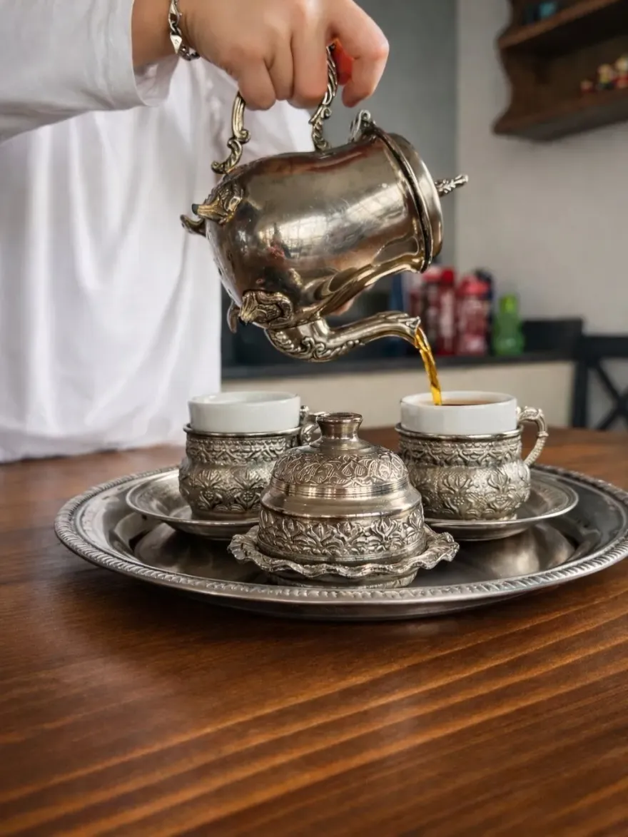 Gümüş çaydanlıktan ince belli bardaklara çay dökülüyor